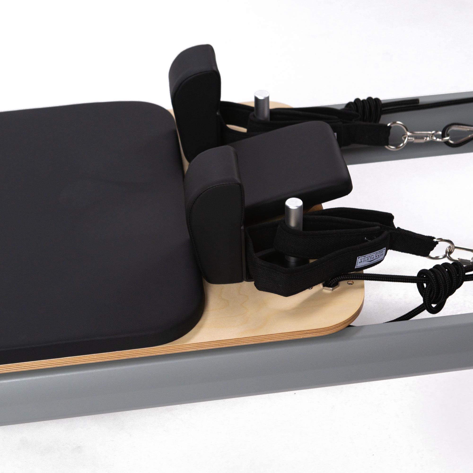 casa Pilates reformer machine with wooden platform and black cushioned seat on a white background